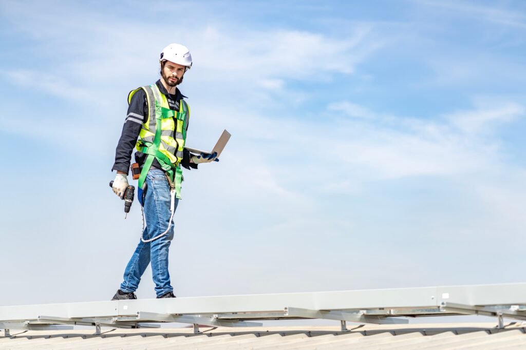 Male engineer installing or checking the working condition of solar panels on the roof