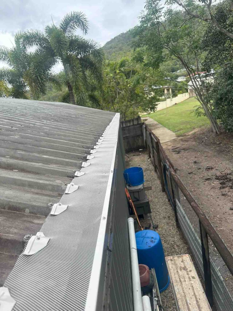 Close-up of aluminium mesh gutter guard installed on metal roof with rainwater tanks